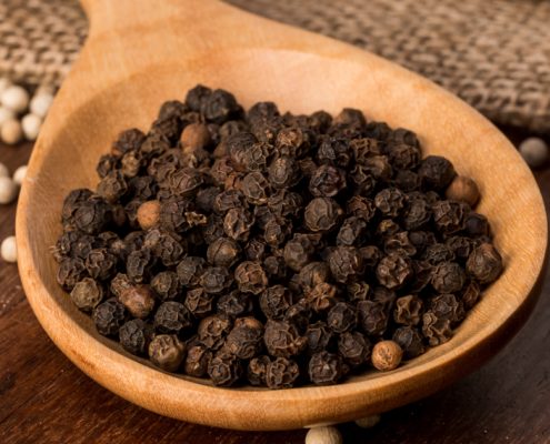 black pepper seeds on a wooden spoon